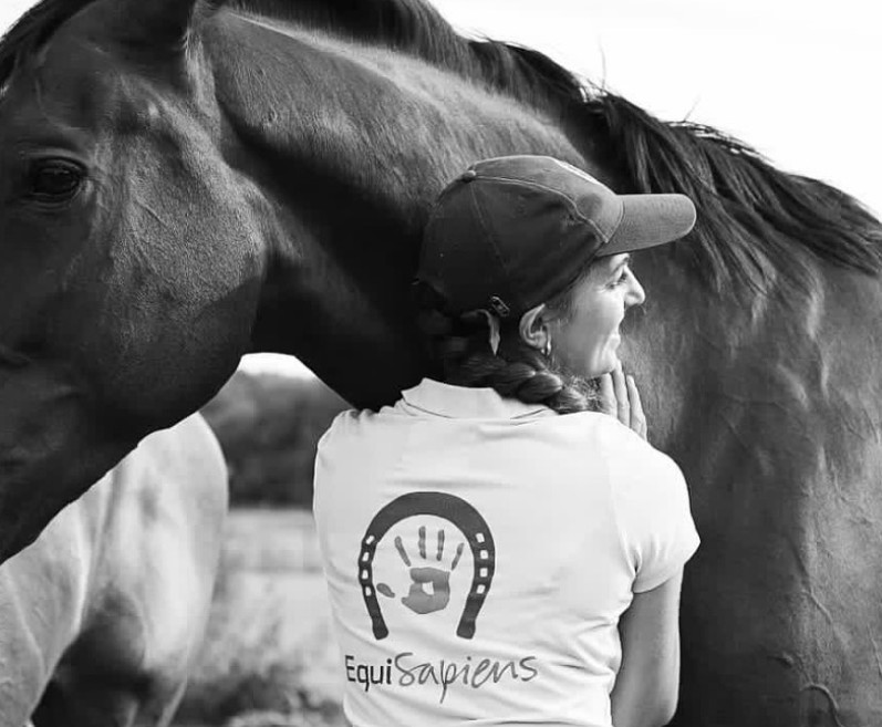 Persona con remera de Equisapiens acariciando un caballo, en blanco y negro