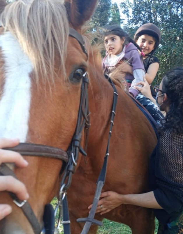 Niña junto a su mamá interactuando con un caballo terapéutico
