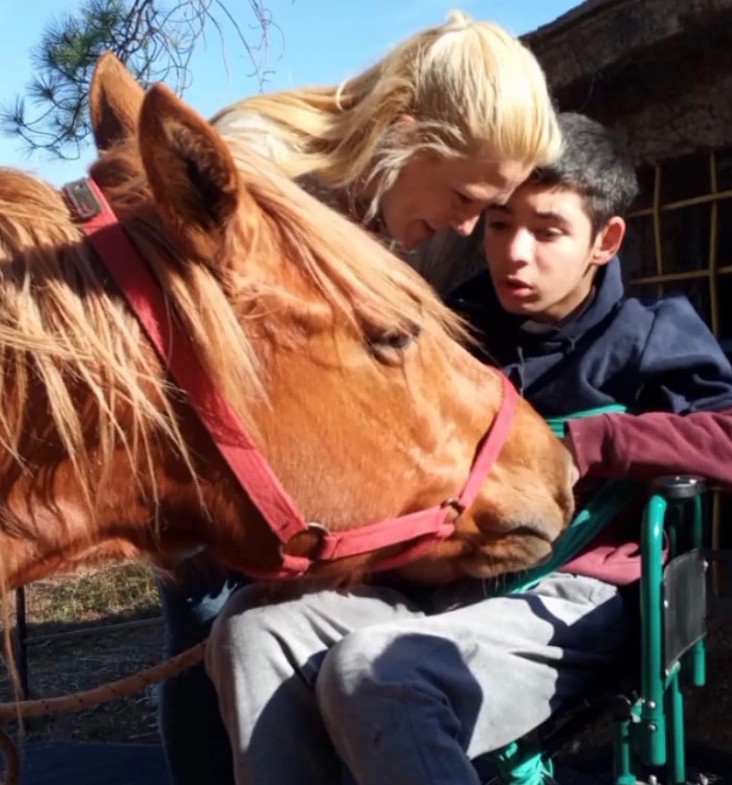 Joven acariciando a un caballo durante una sesión de equinoterapia